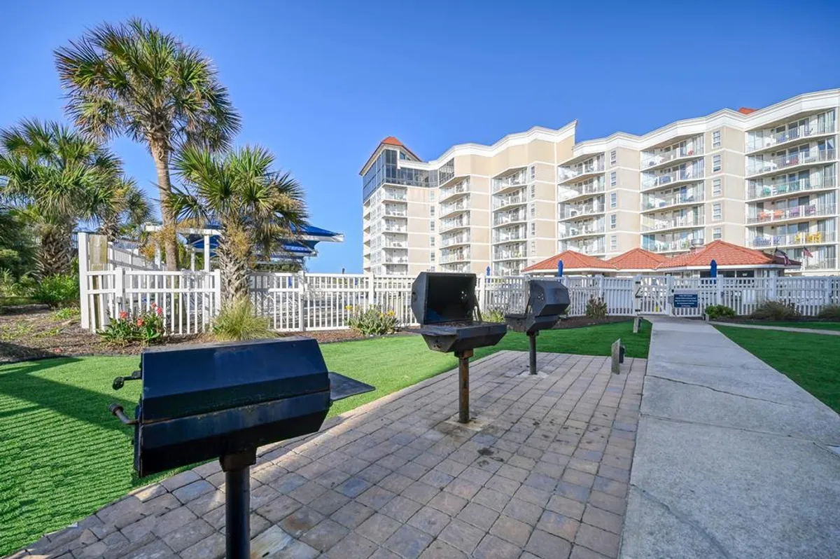 An exterior shot showcases a landscaped communal grilling area with multiple grills, palm trees, and the condo building in the background. Residents gather here for barbecuing, socializing, and enjoying outdoor meals together.