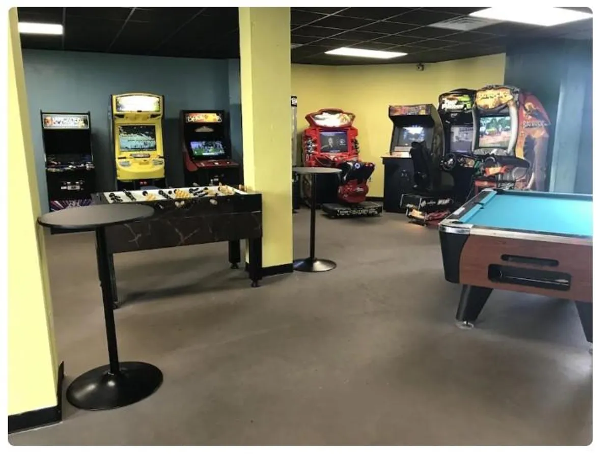 A lively game room filled with arcade machines, a pool table, and a foosball table, ready for family fun and friendly competition. The setting is vibrant, playful, and designed for all ages.