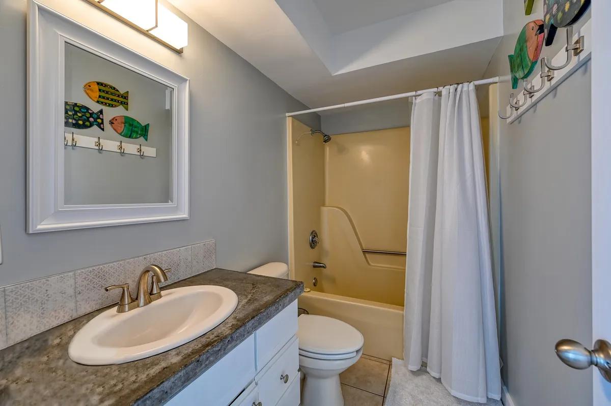 A bright, cheerful bathroom with a colorful fish-themed artwork, a modern sink, and a shower area. The design is playful yet functional, providing a welcoming space for morning and nighttime routines.