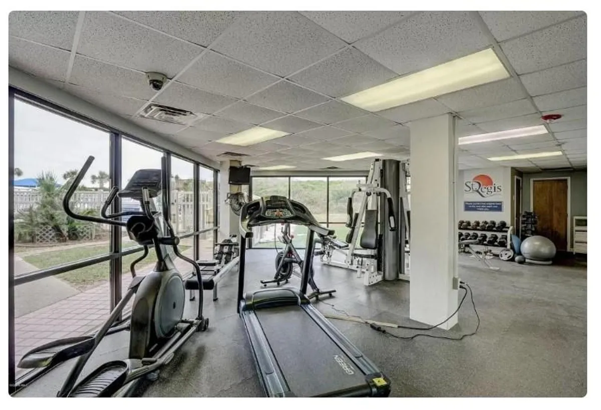 A bright, modern fitness center is shown, equipped with treadmills, elliptical machines, weights, and expansive windows that let in natural light. The space conveys energy and motivation, perfect for active lifestyles.